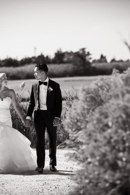 Bride and groom walk down a path holding hands