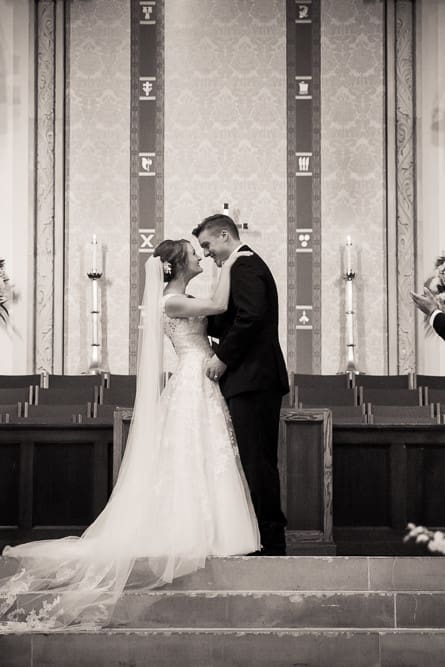 bride and groom kissing at the altar during wedding ceremony