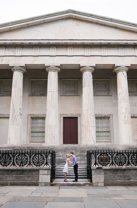 Rebecca and Lyall leaning in for a kiss in front of the 2nd Bank of The United States in Philadelphia