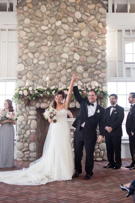 Bride and groom holding up hands in celebration of their wedding