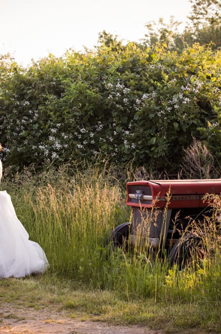 bride and groom by antique mower at their Gansett Green Manor wedding