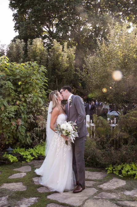 Lindsey and Tommy stop for a kiss in the garden of Bedell Cellars after their ceremony