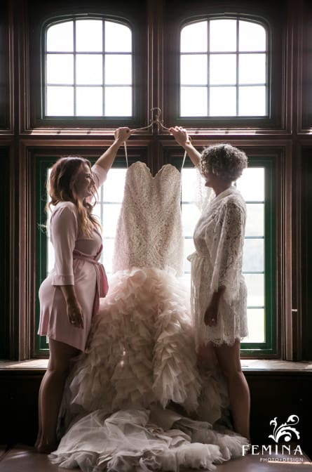 Michelle and her bridesmaid hold up her wedding dress at Saint Andrews School in Delaware