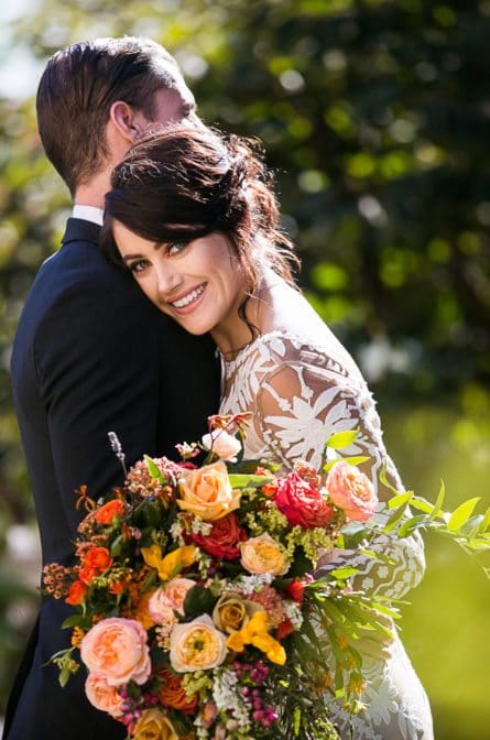 Brook smiles as she leans on Tony's shoulder with her bouquet