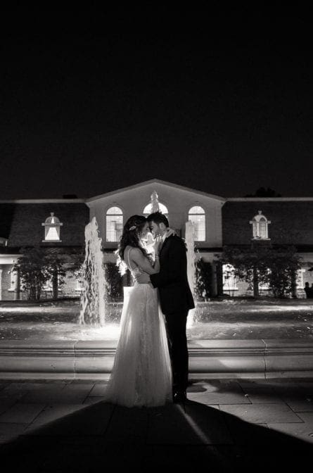 Bride and groom posing in front of the fountain at night at The Rockleigh