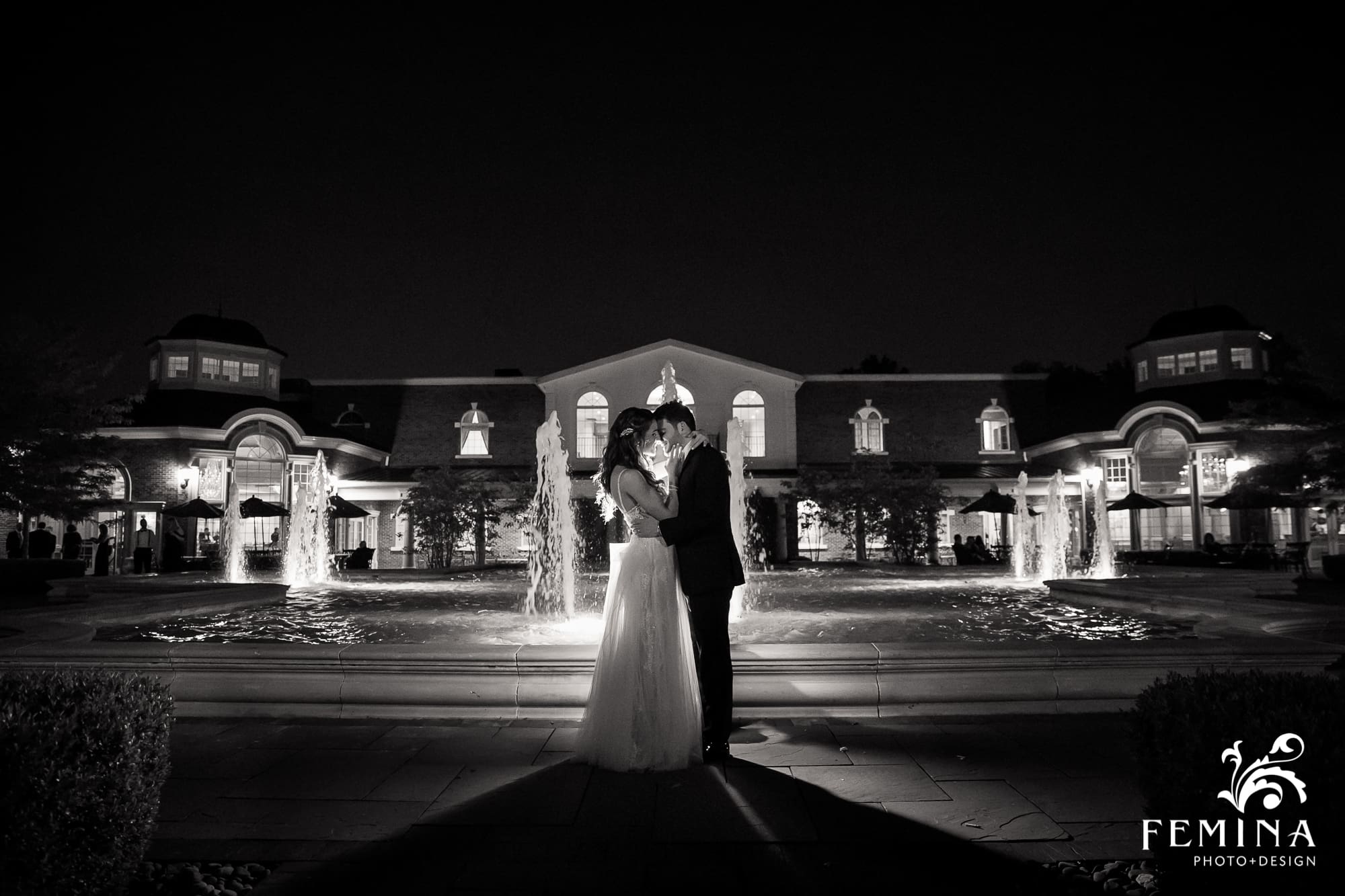 Bride and groom posing in front of the fountain at night at The Rockleigh