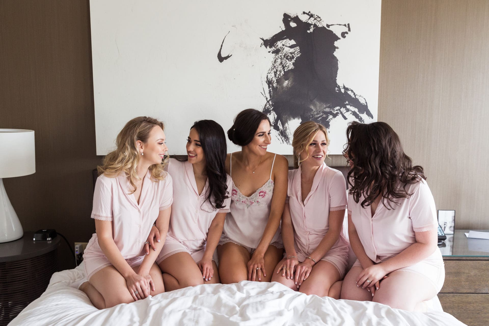 Bridesmaids on the bed laughing during getting ready