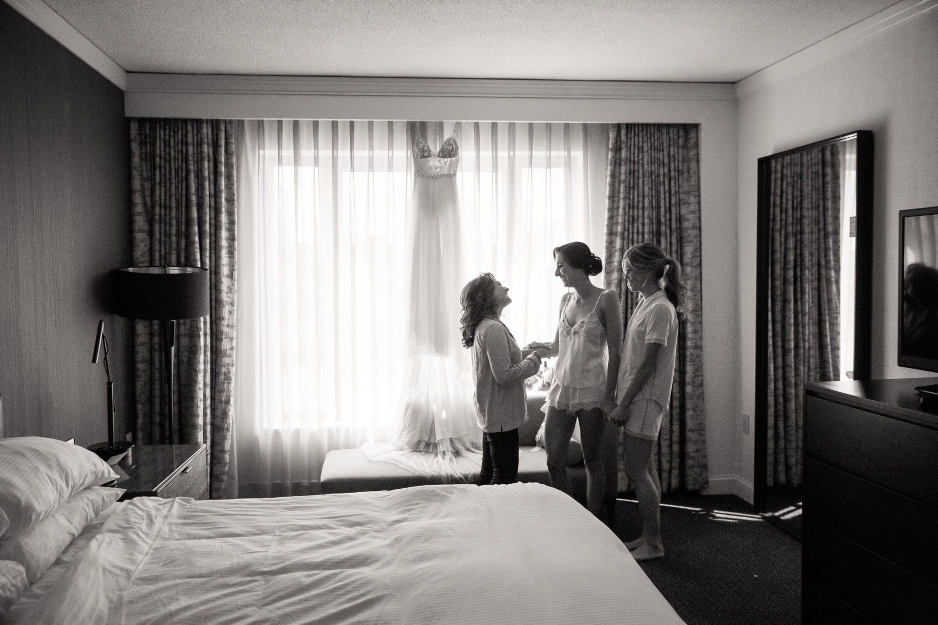 Bride and her mom holding hands and laughing during getting ready at the Logan hotel