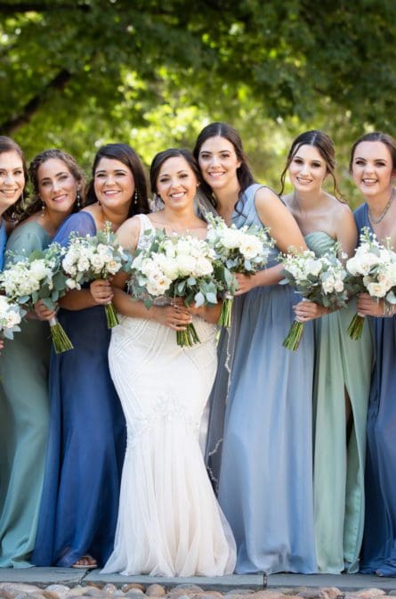 Bride and her bridesmaids huddled together and smiling at the camera behind the Second National Bank of the United States in Philadelphia