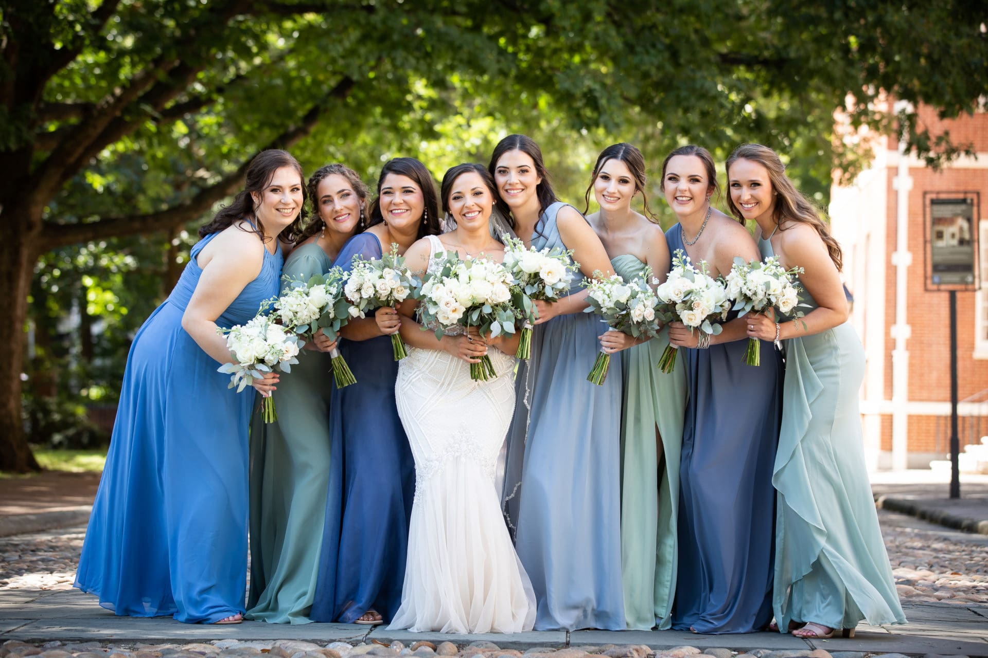Bride and her bridesmaids huddled together and smiling at the camera behind the Second National Bank of the United States in Philadelphia