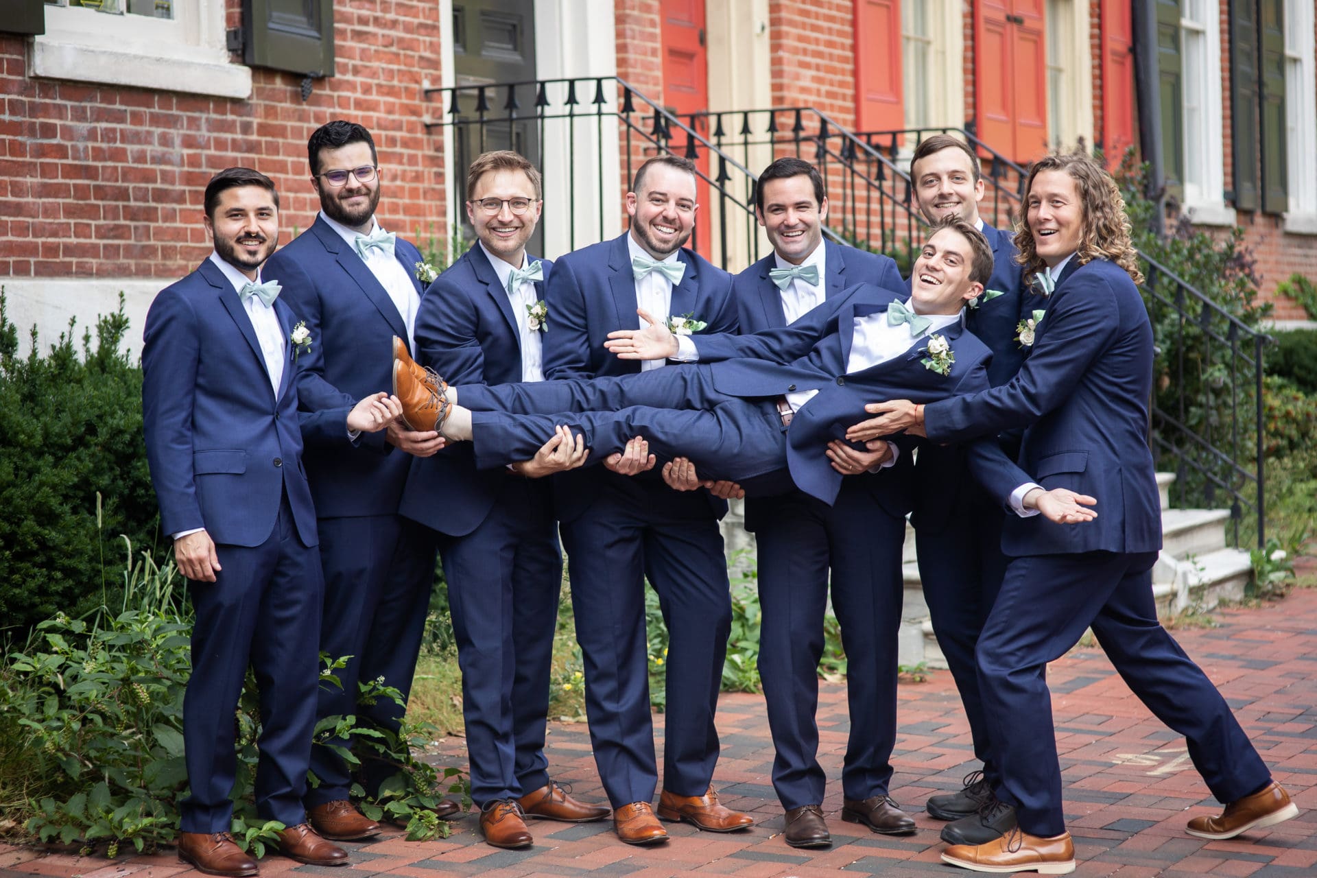Groomsmen holding the groom sideways and laughing