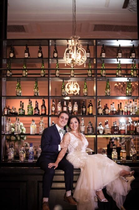 Bride and groom posing on the bar inside their ballroom at the Cesacphe Ballroom in Philadelphia