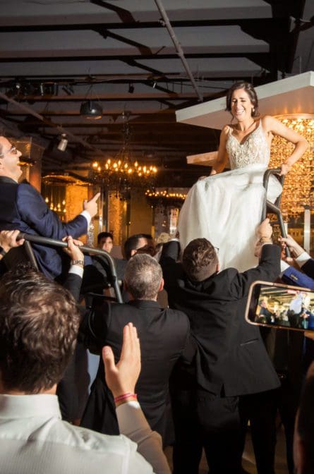Bride and groom getting lifted up on chairs during the reception