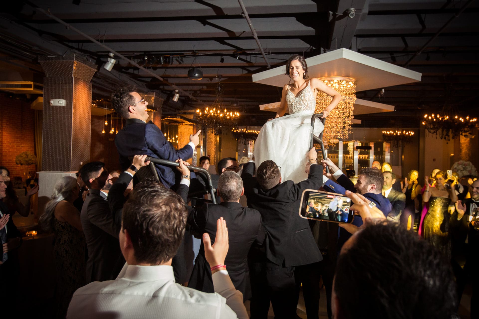 Bride and groom getting lifted up on chairs during the reception