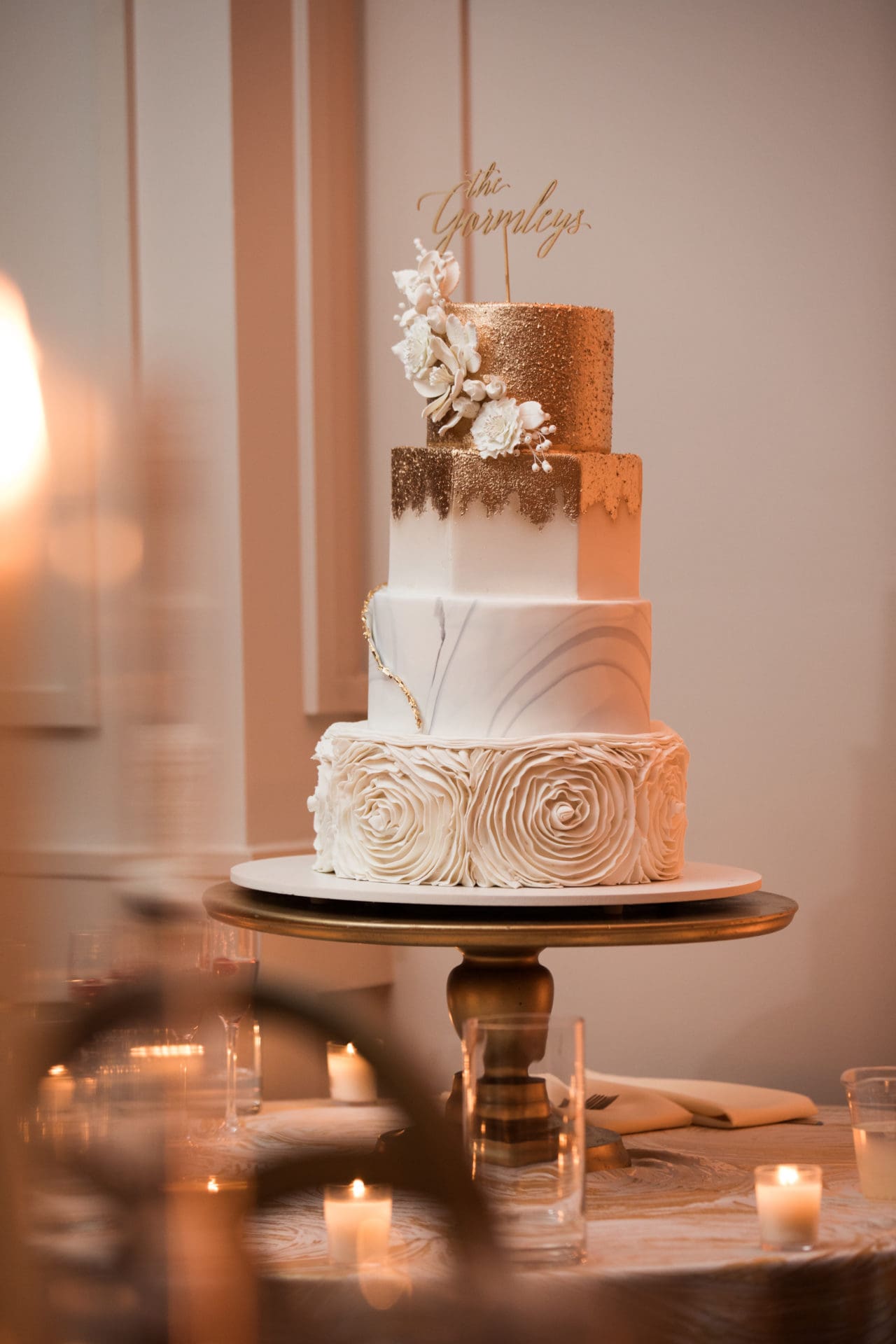 A four tiered wedding cake that is ivory and gold