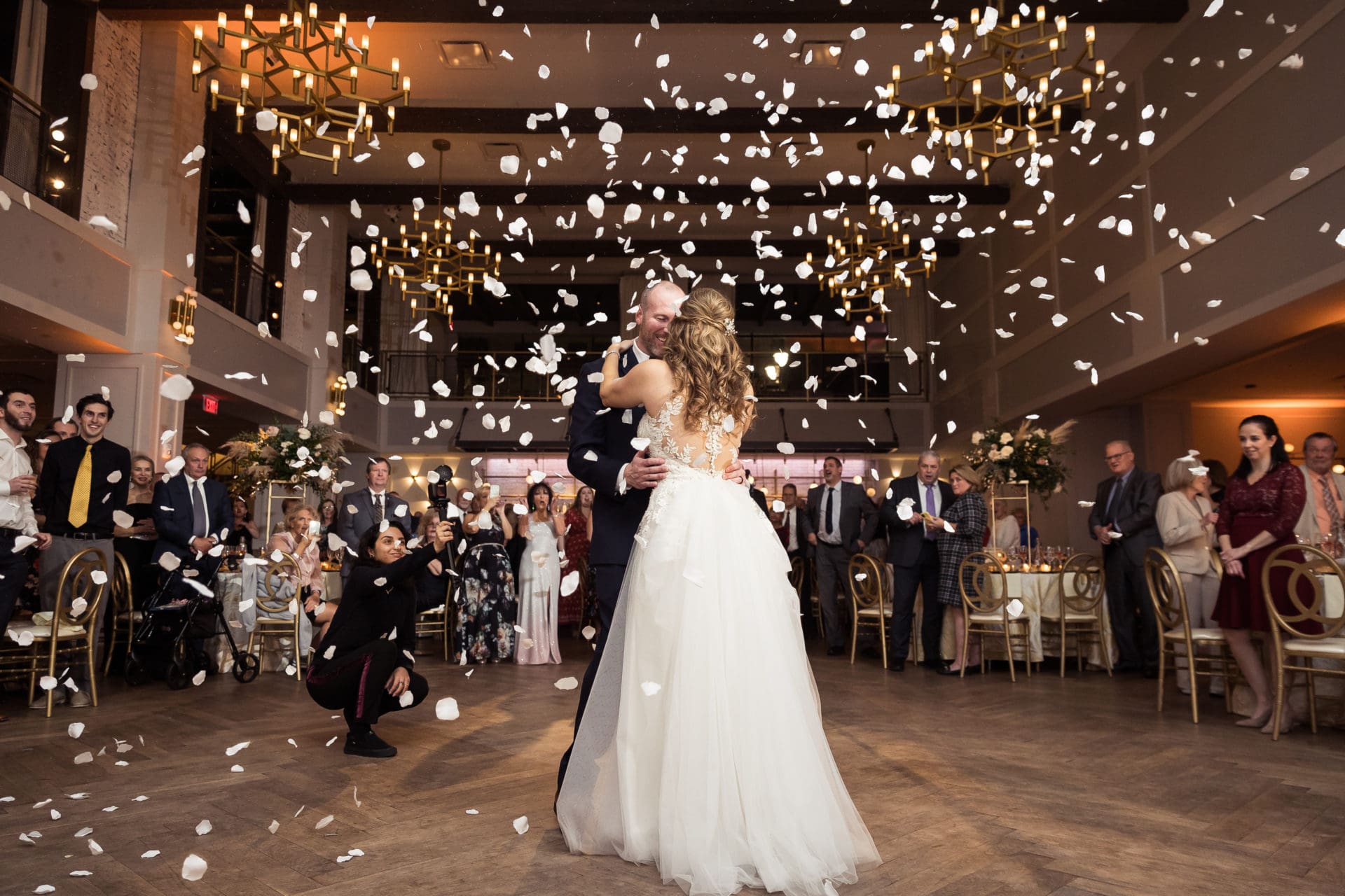 Bride and groom dancing during their first dance with a flower canon shooting white rose petals onto the dance floor