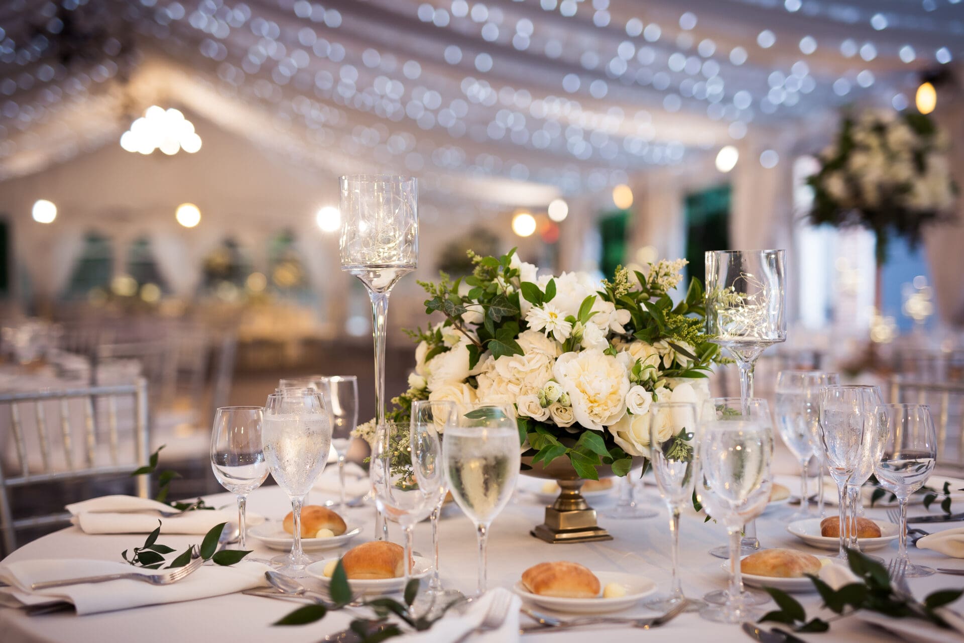 Close up of table decor with tall glass vases and candles in a large reception room at Lyndhurst Castle