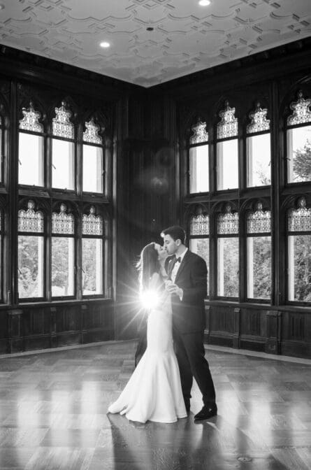 A bride and groom are dancing in an empty ballroom at Hempstead House and the image is in black and white.