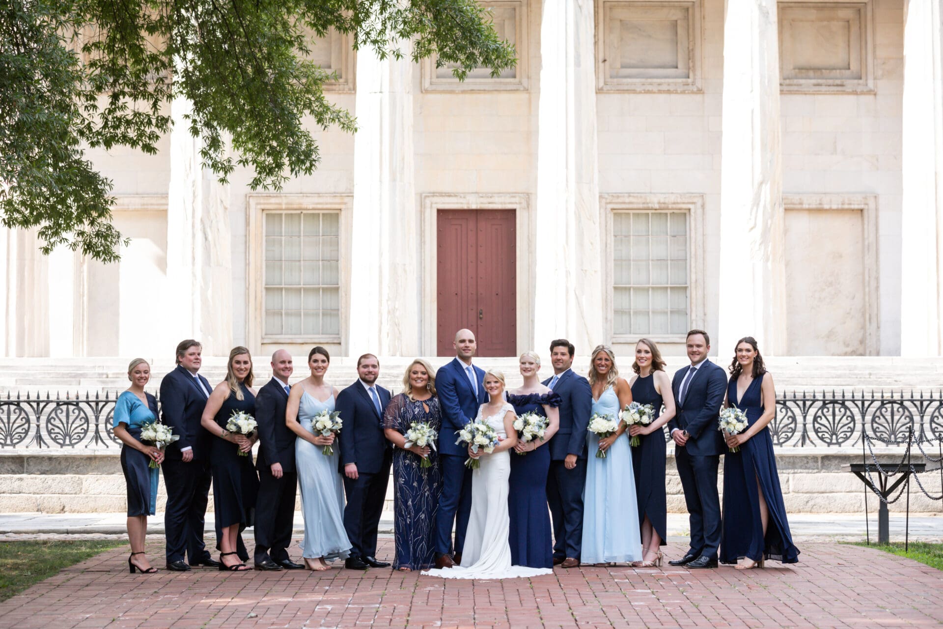 And bride and groom and their wedding party posing in front of the Second National Bank of the United States in Old City Philadelphia