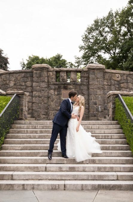 Bride and groom kissing on the steps in the Rose Garden at their NYBG Stone Mill wedding