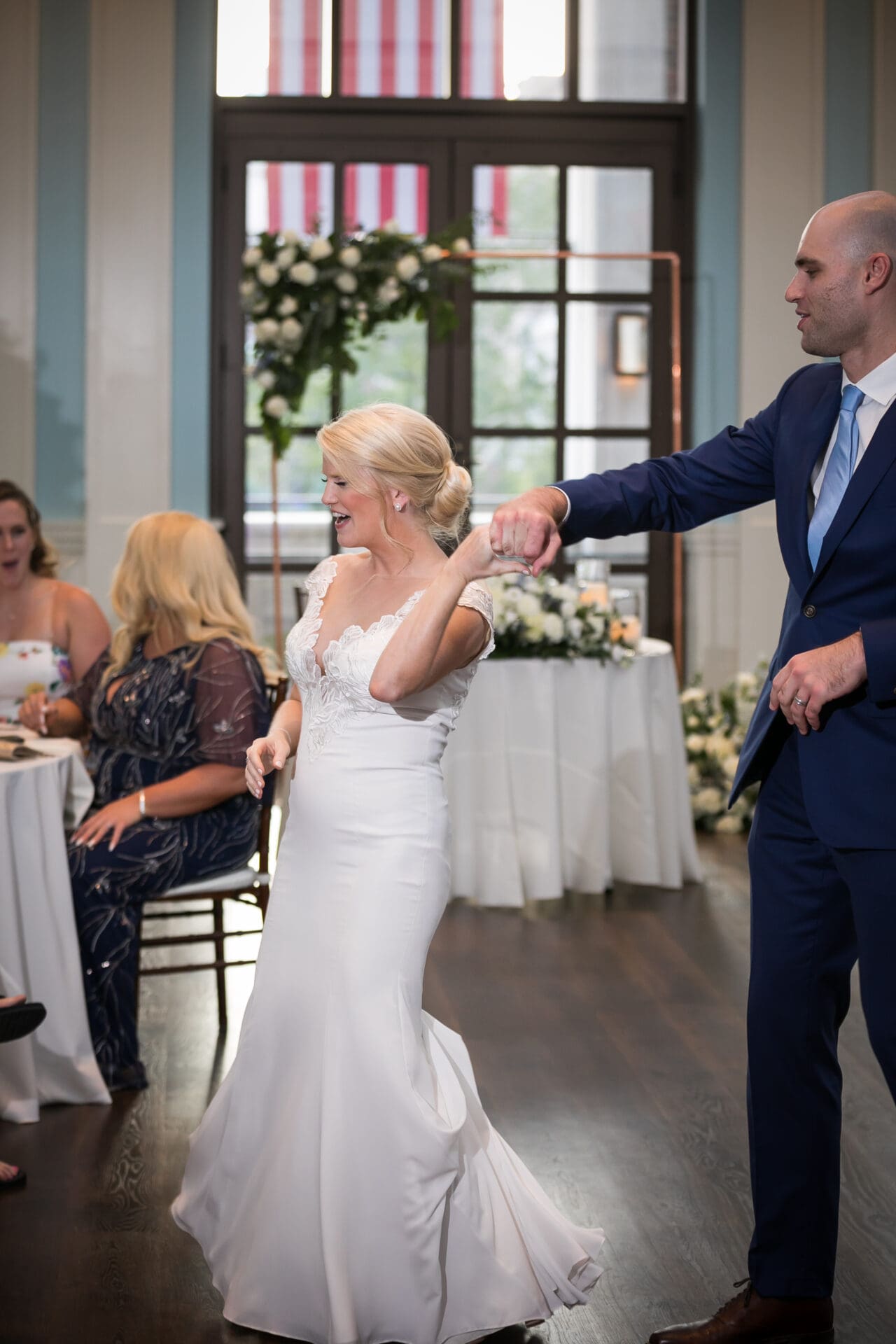 A groom is twirling his bride on the dance floor during their first dance at their wedding reception