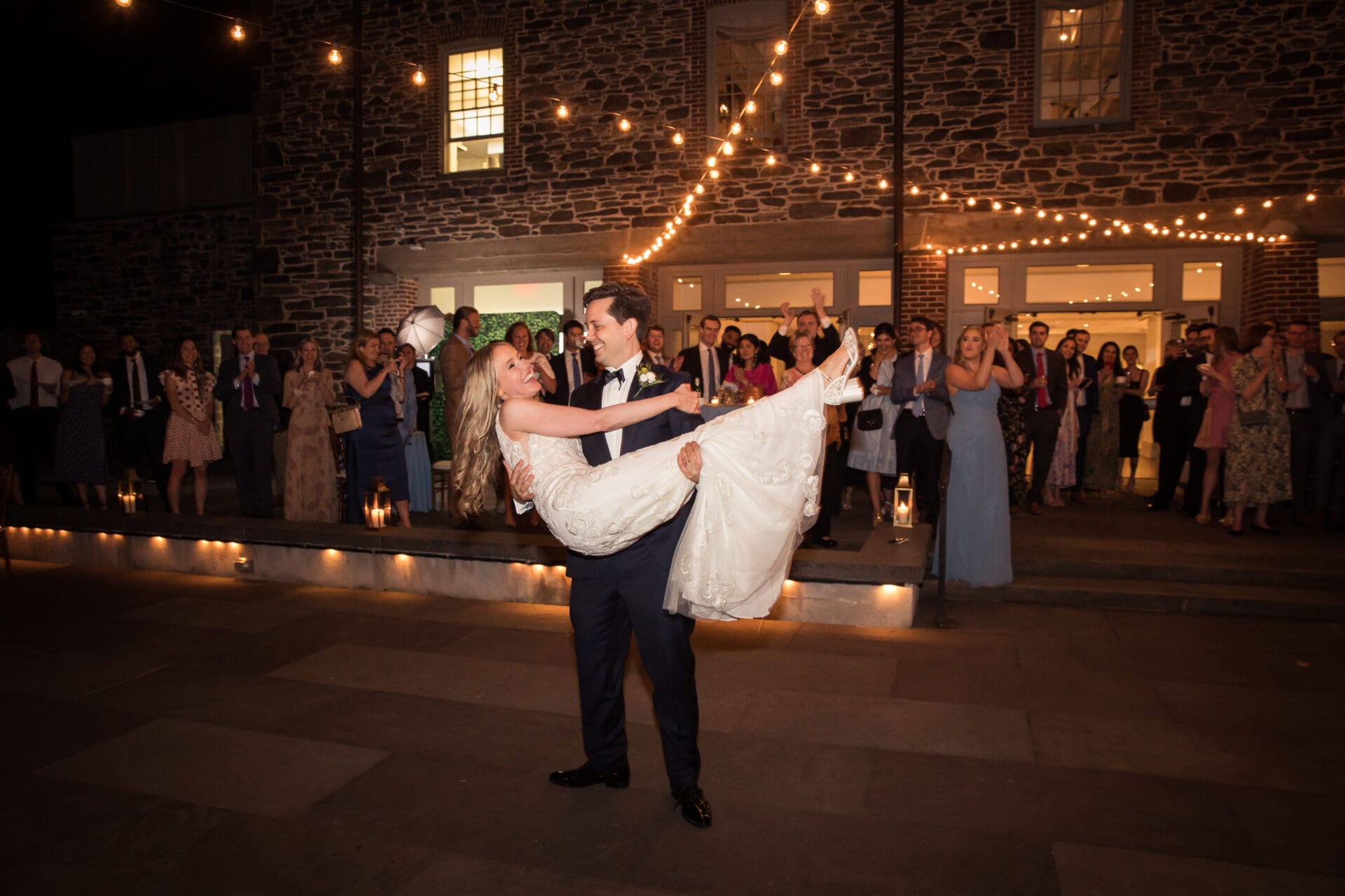 A groom is twirling his bride around the dance floor during their NYBG Stone Mill wedding